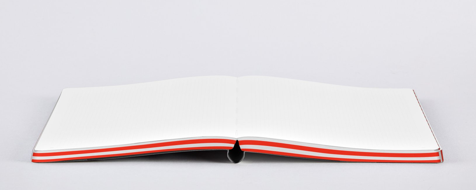 Notatnik graficzny L firmy BV JACOB COMPANY otwarty na pustych kartkach z czerwonym paskiem na krawędzi