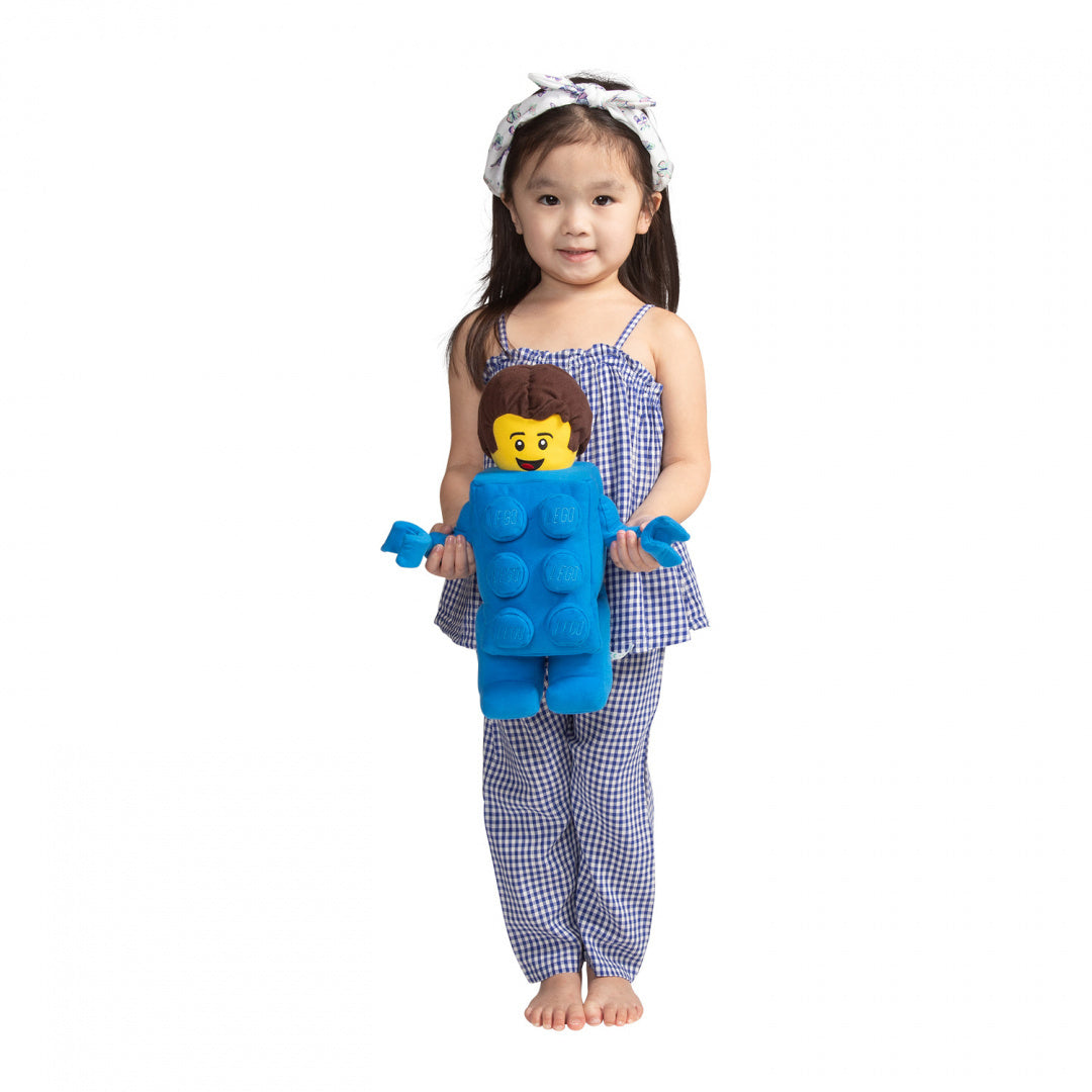 Dziewczynka trzyma pluszak LEGO Brick Suit Boy w niebieskim stroju z uśmiechniętą twarzą