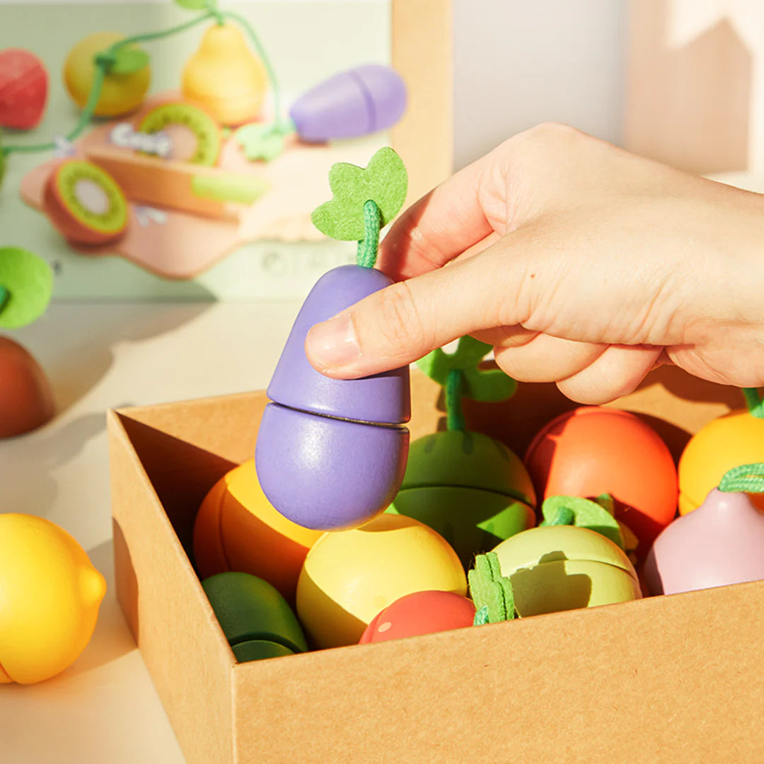 Zestaw drewniane owoce i warzywa do krojenia w pudełku z fioletową bakłażanem w dłoni