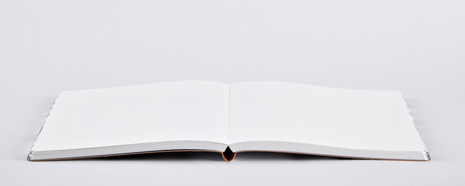 Notatnik artystyczny czarno-biały otwarty na białym tle z pustymi kartkami