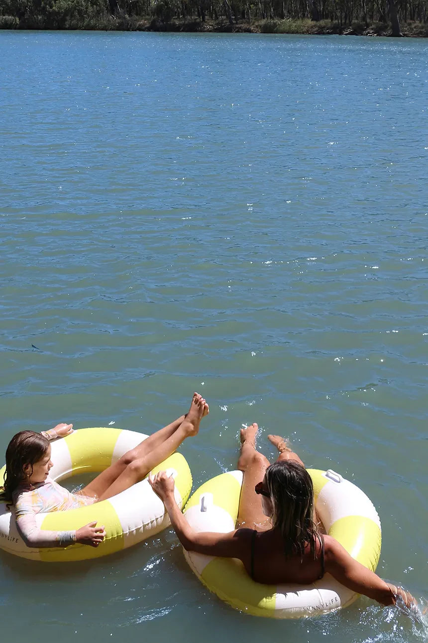 Dwie kobiety relaksujące się na żółto-białym kole do pływania dla dorosłych na jeziorze