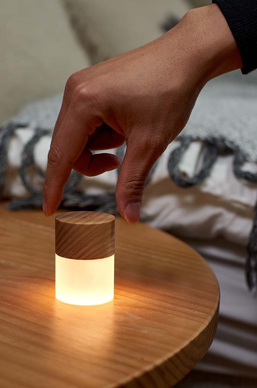 Lampka nocna z drewna jesionowego na drewnianym stoliku z ręką wyłączającą światło