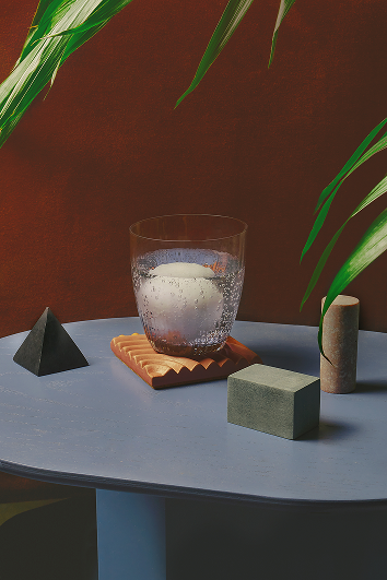 Szklanka z kostką do napoju na oryginalnej podstawce obok geometrycznych kostki do napojów design