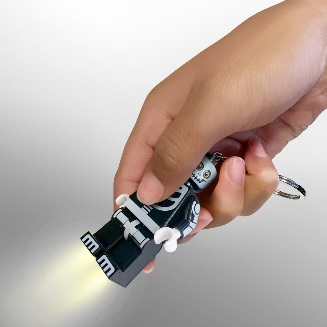 Brelok LEGO z latarką w kształcie czarno-białej figurki szkieletu trzymany w dłoni