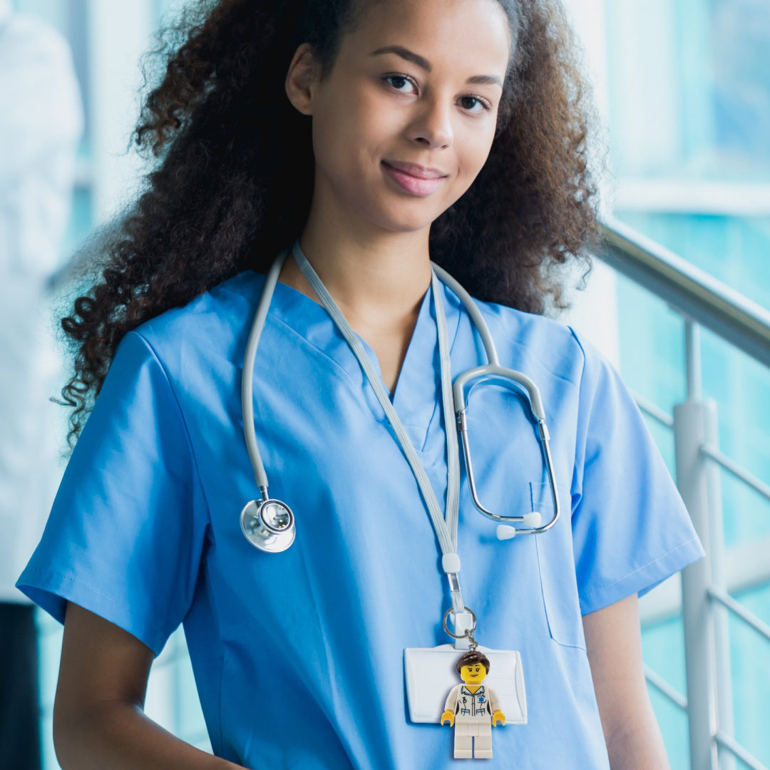 Brelok pielęgniarka LEGO przypięty do identyfikatora na uniformie pielęgniarki z stetoskopem