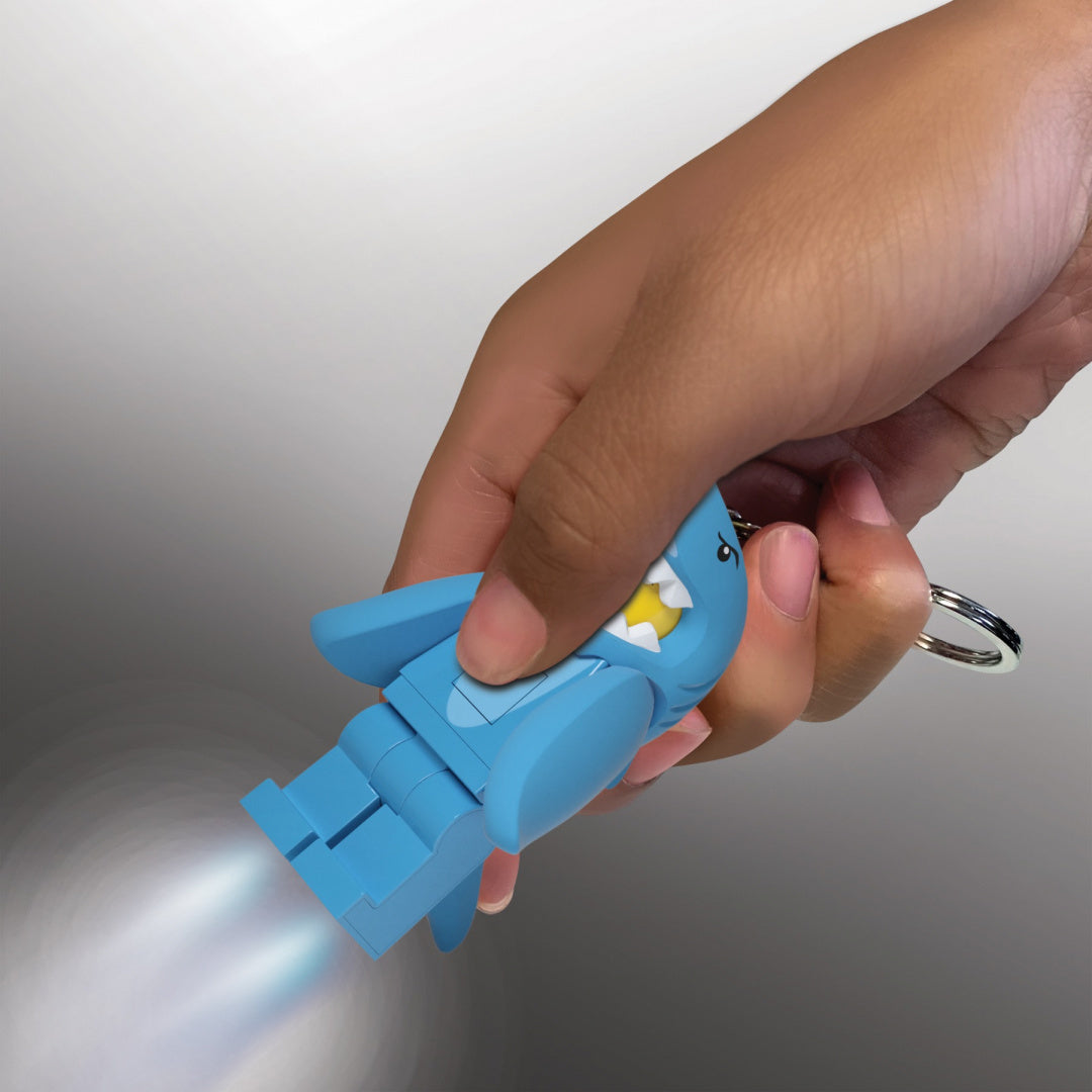 Brelok LEGO z latarką w kształcie niebieskiego rekina trzymany w dłoni z włączonym światłem latarki