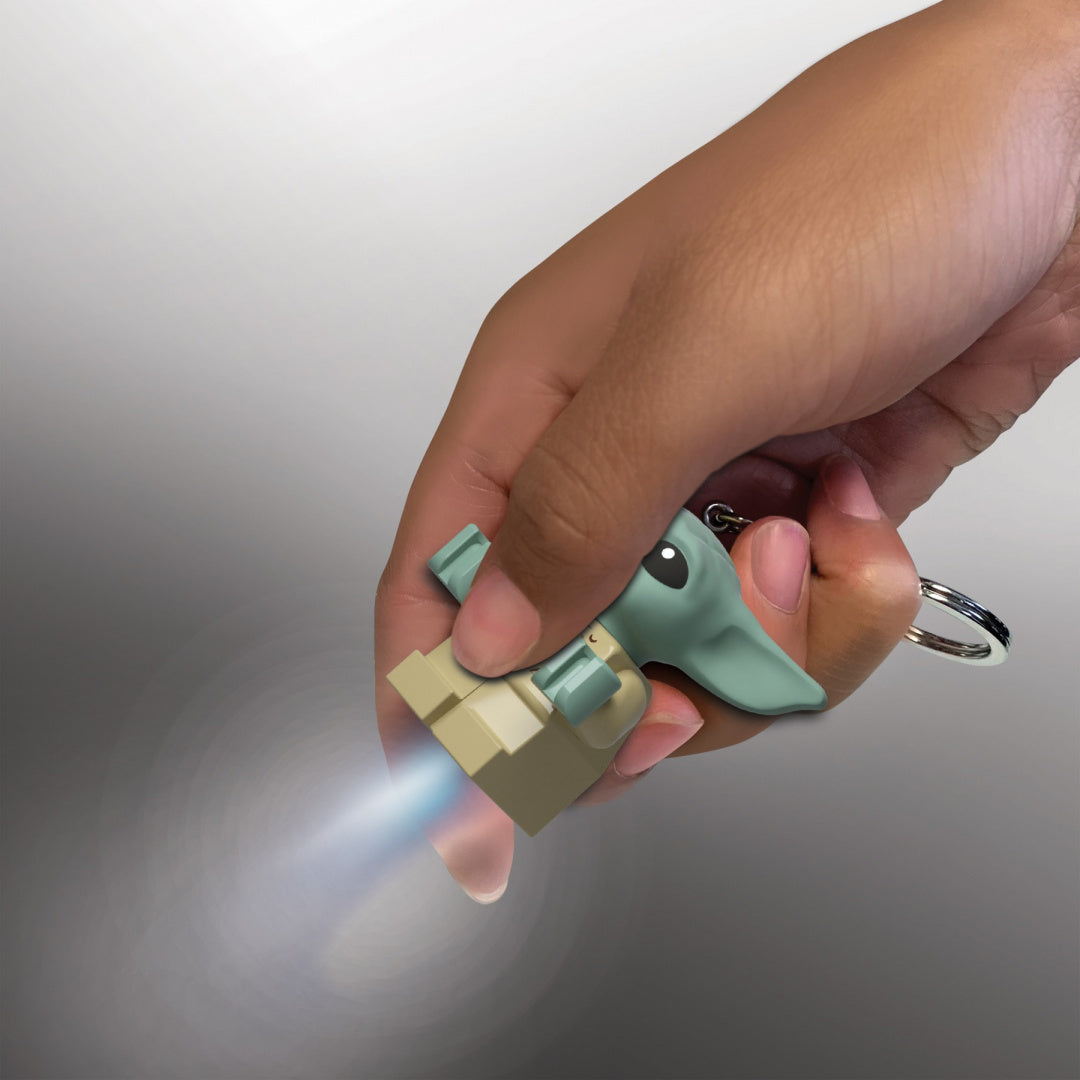 Brelok ze światłem LED w kształcie postaci Baby Yoda trzymany w dłoni