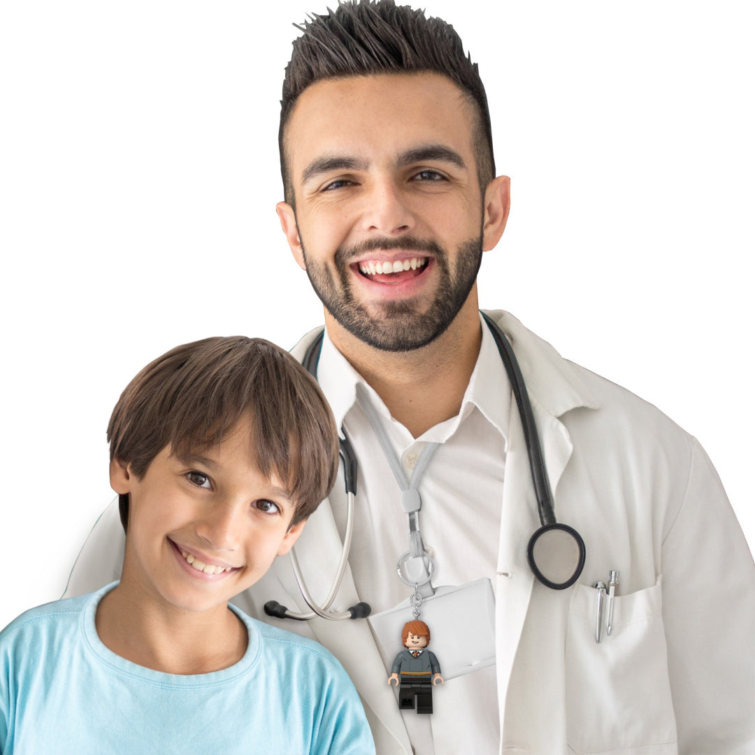 Brelok LEGO Harry Potter przypięty do identyfikatora u lekarza z dzieckiem w białym tle