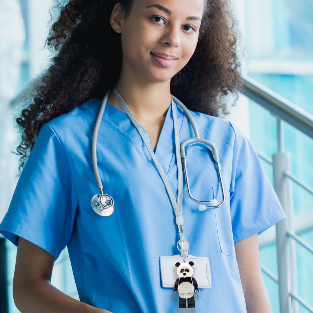 Brelok LEGO panda zawieszony na identyfikatorze pielęgniarki w niebieskim uniformie medycznym