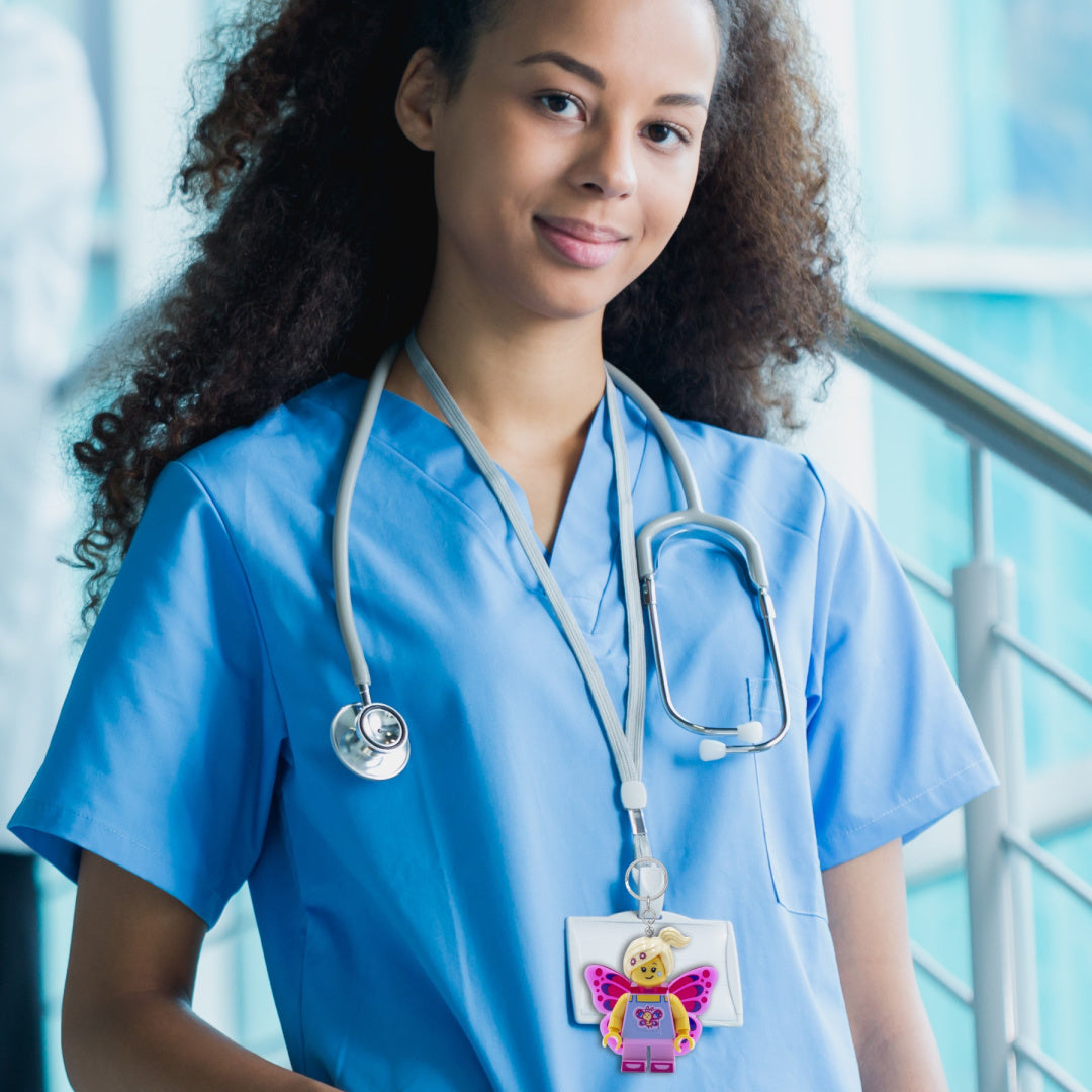 Brelok z latarką LEGO motylek przypięty do identyfikatora na szyi kobiety w niebieskim uniformie medycznym