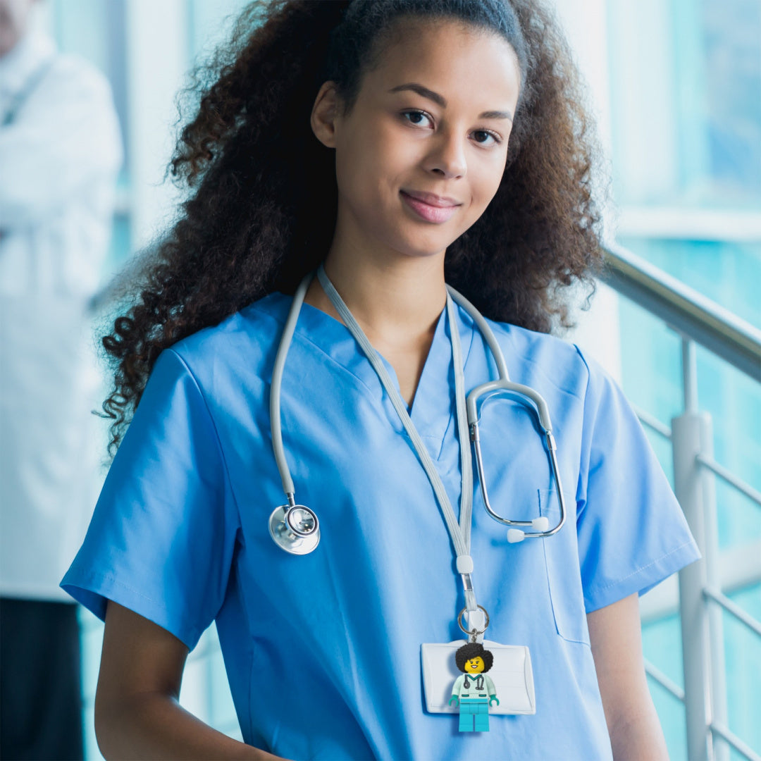 Brelok LEGO z latarką przypięty do identyfikatora młodej kobiety w niebieskim uniformie medycznym