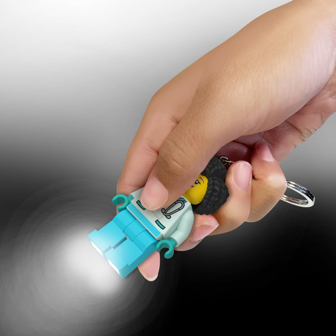 Brelok LEGO z latarką w kształcie postaci LEGO z niebieskimi spodniami trzymany w dłoni