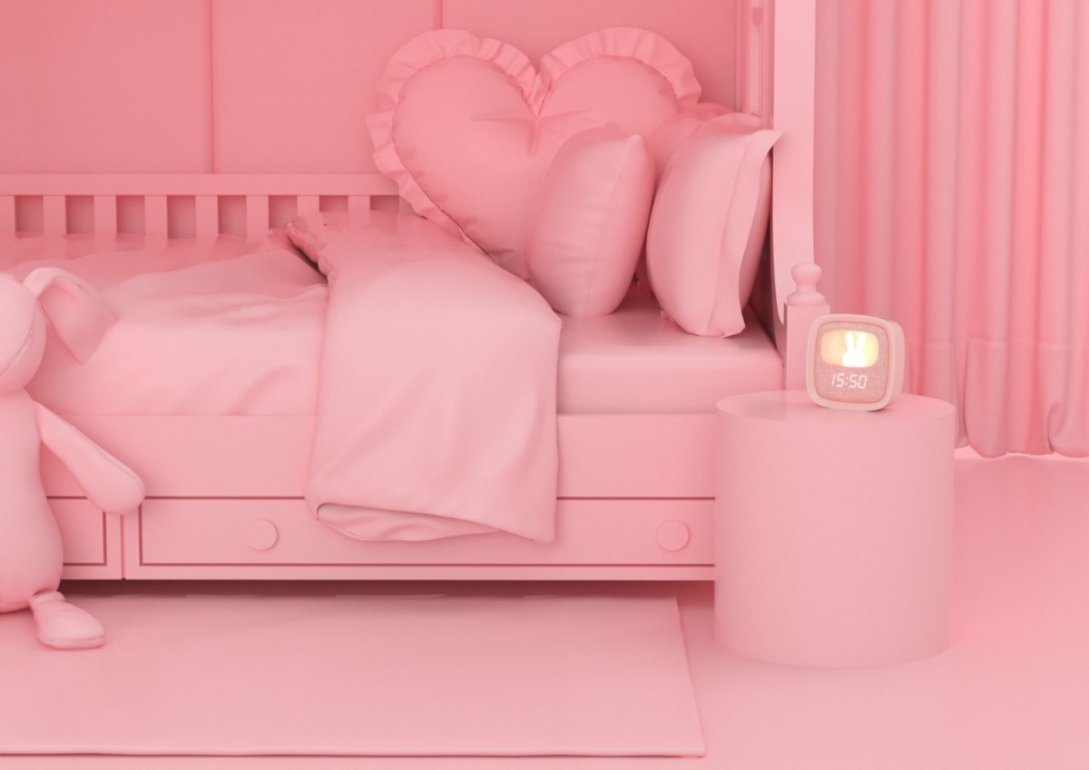 Budzik dla dzieci z lampką na stoliku przy różowym łóżku w pokoju dziecięcym