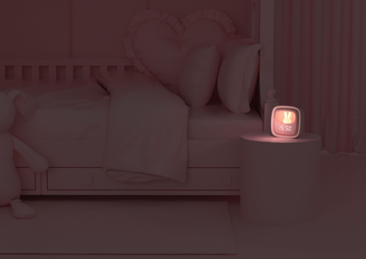 Budzik dla dzieci z lampką na stoliku nocnym obok łóżka w dziecinnym pokoju