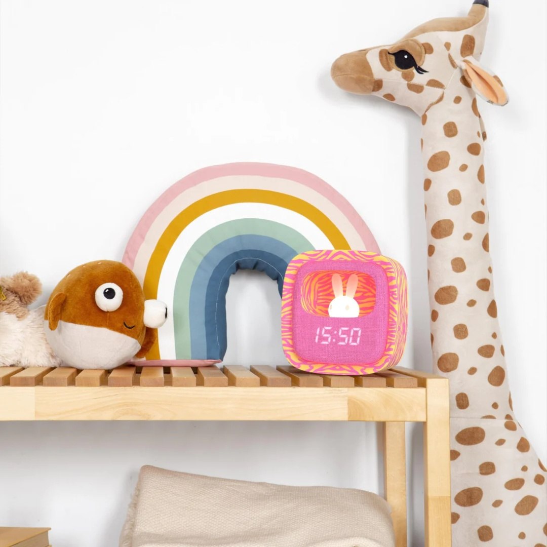 Kolorowy budzik dla dzieci z lampką wyświetlający czas na półce obok zabawek
