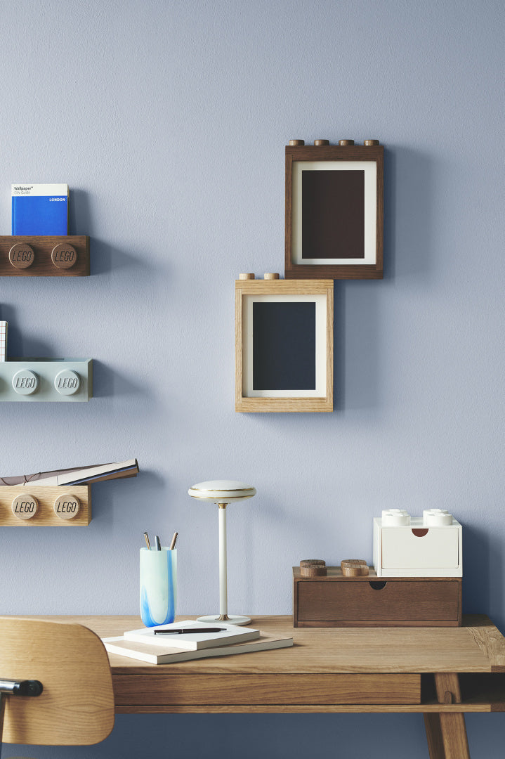 Drewniana ramka LEGO na zdjęcia w dwóch odcieniach na ścianie nad biurkiem w nowoczesnym wnętrzu