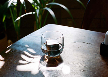 Szklanka z napojem i kostki do napojów design na drewnianym stole w naturalnym świetle