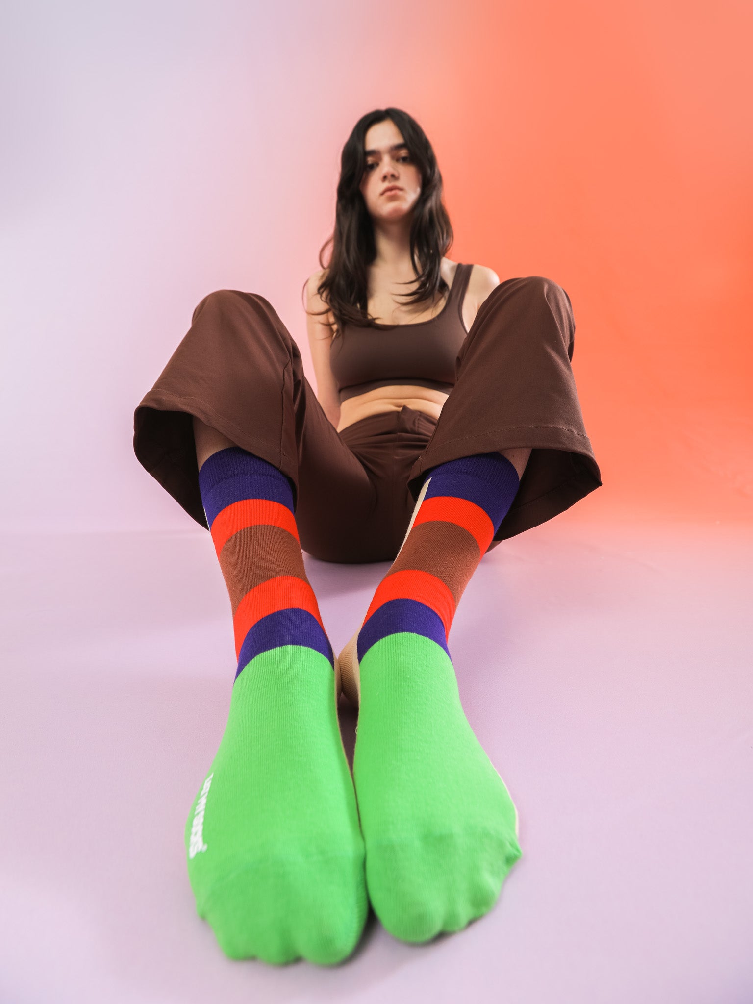 Kolorowe skarpetki döner kebab na stopach młodej kobiety siedzącej na podłodze w brązowym stroju