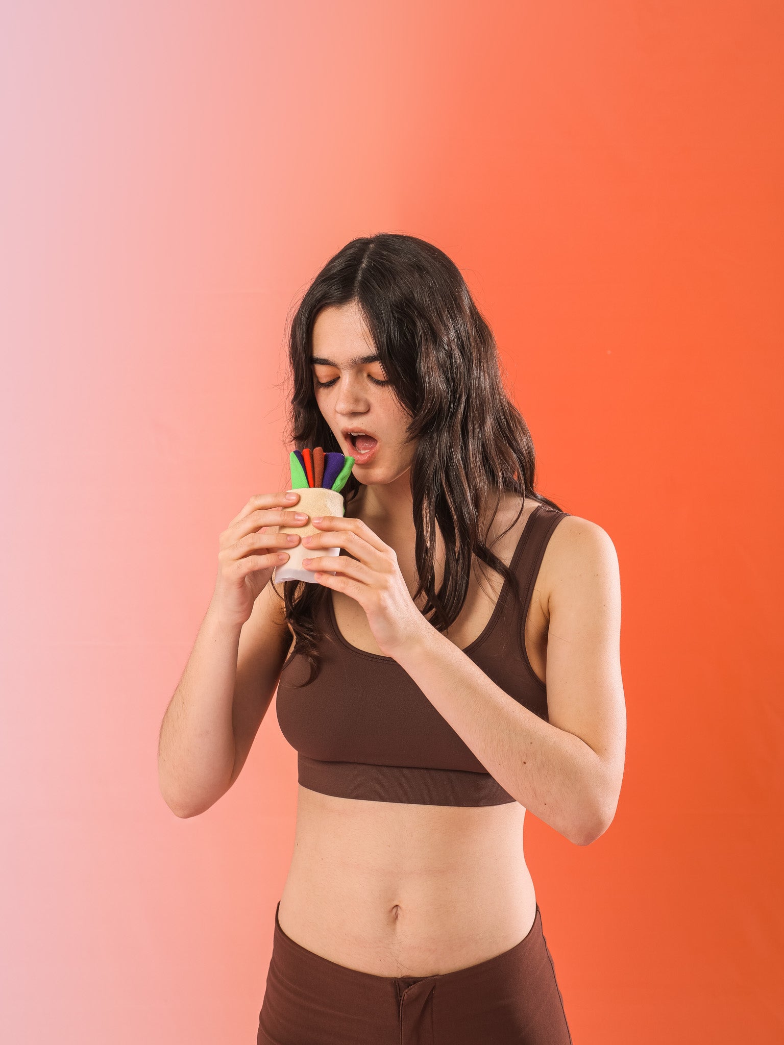 Kobieta w brązowym stroju sportowym trzymająca i patrząca na skarpetki döner kebab na pomarańczowym tle