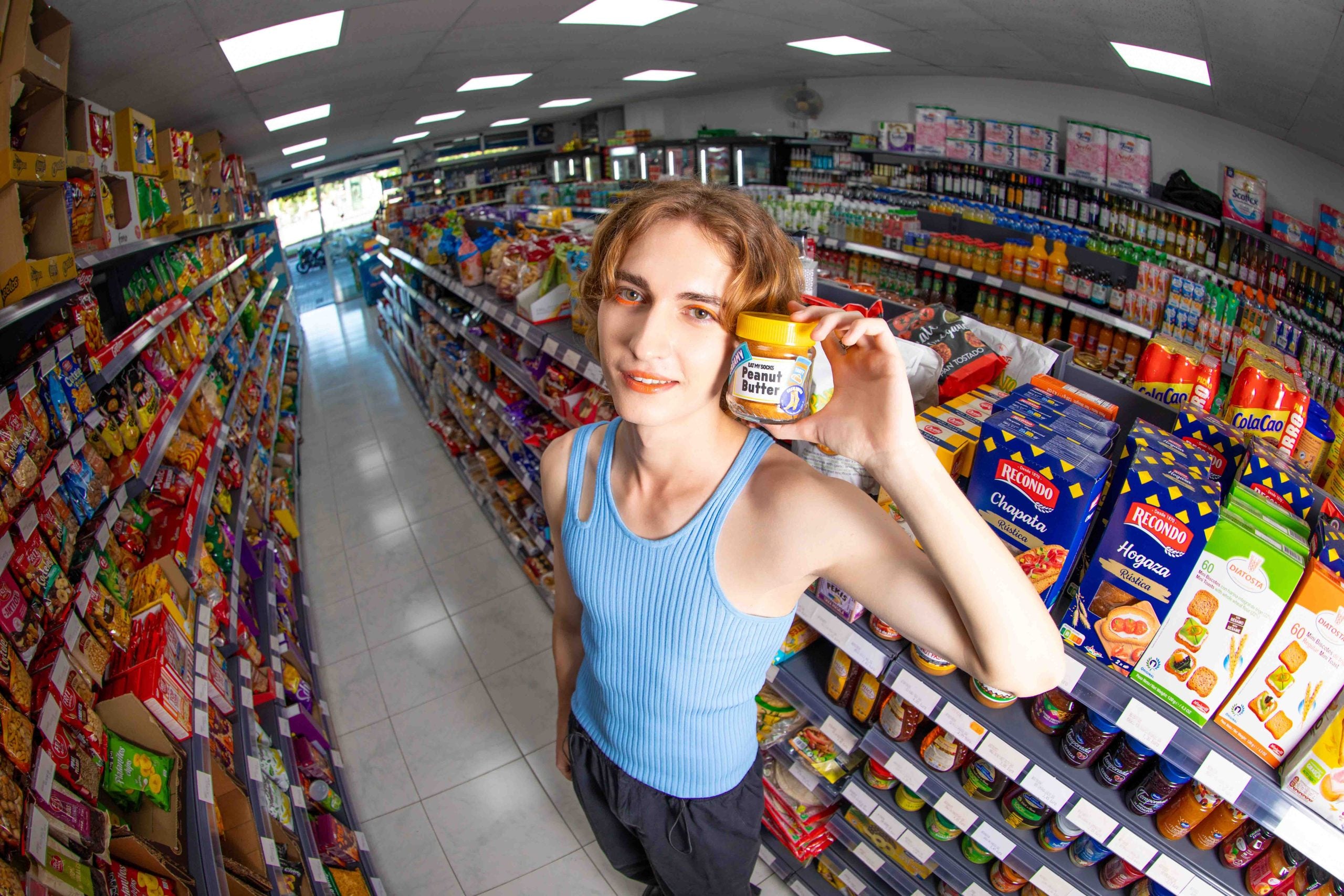 Młoda kobieta w sklepie trzyma słoik masła orzechowego skarpetki peanut butter na tle półek z produktami spożywczymi