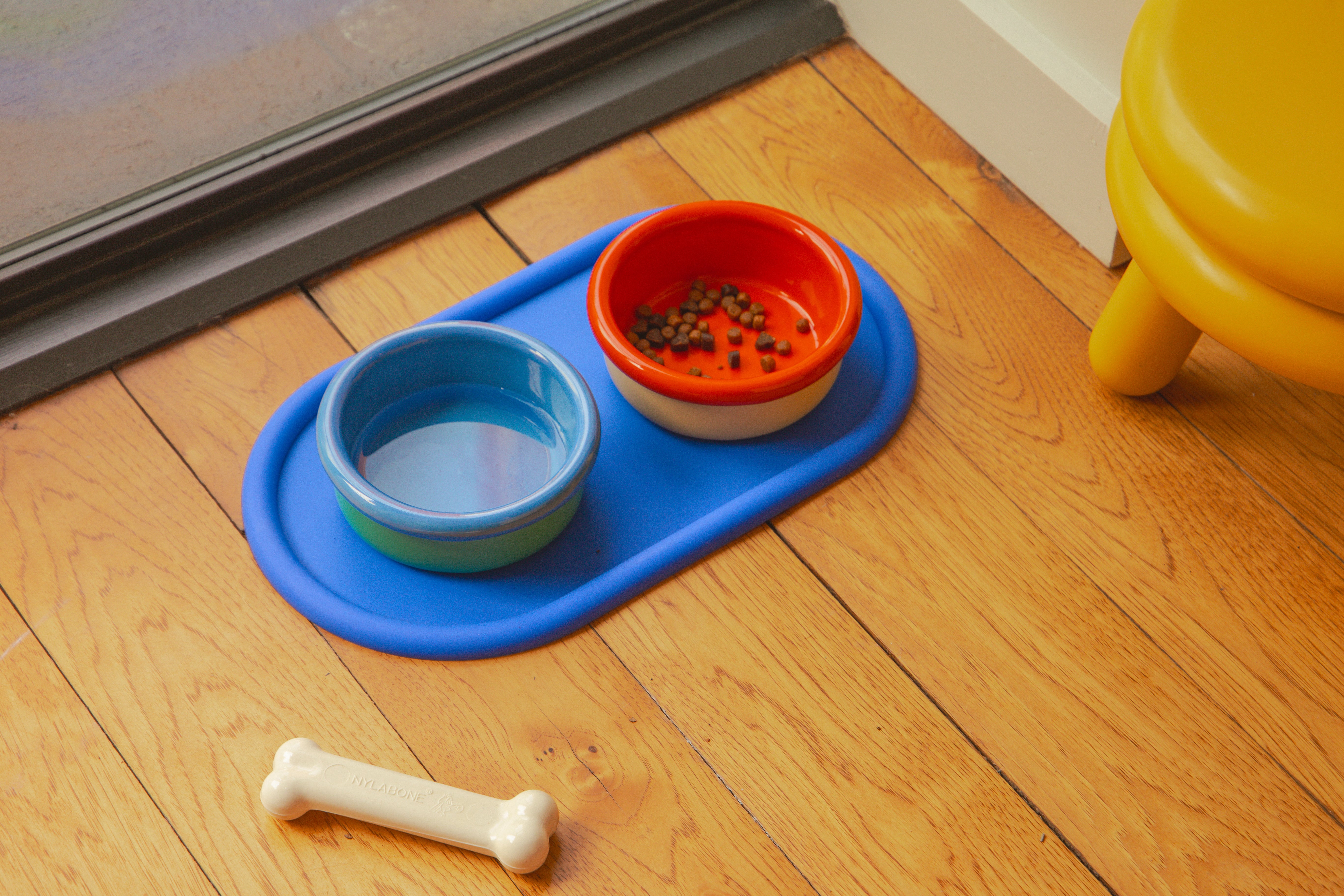 Zestaw miseczek dla zwierząt Areaware z dwoma kolorowymi miskami na wodę i karmę na niebieskiej podstawce