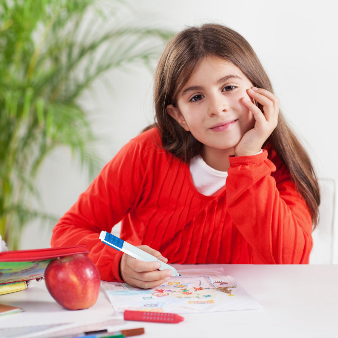 Dziewczynka rysująca obrazek flamastrami LEGO 12 kolorów przy białym stole z jabłkiem