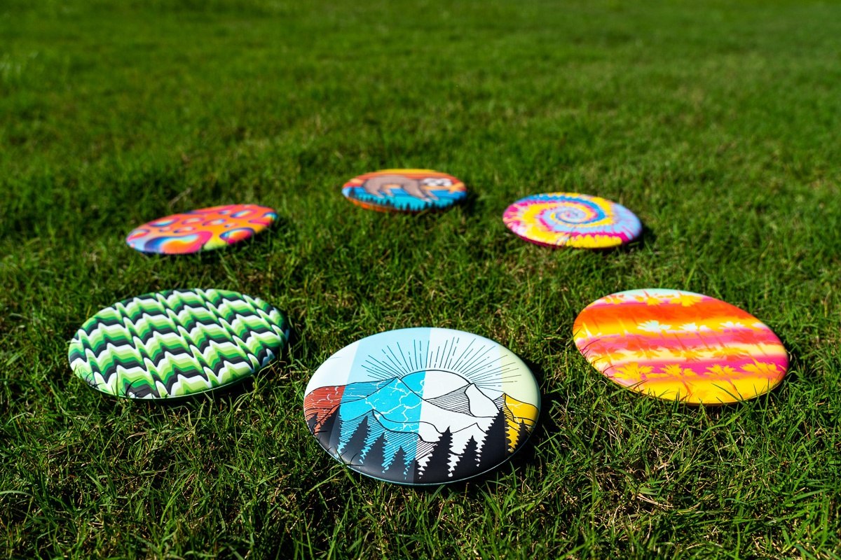 Kolorowe frisbee Waboba Wingman z różnymi wzorami leżące na zielonej trawie