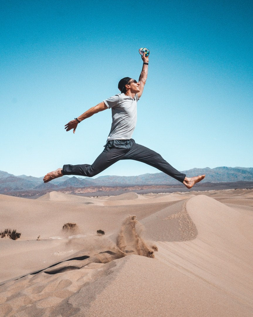 Mężczyzna skaczący na pustyni rzuca frisbee Waboba Wingman w pogodny dzień