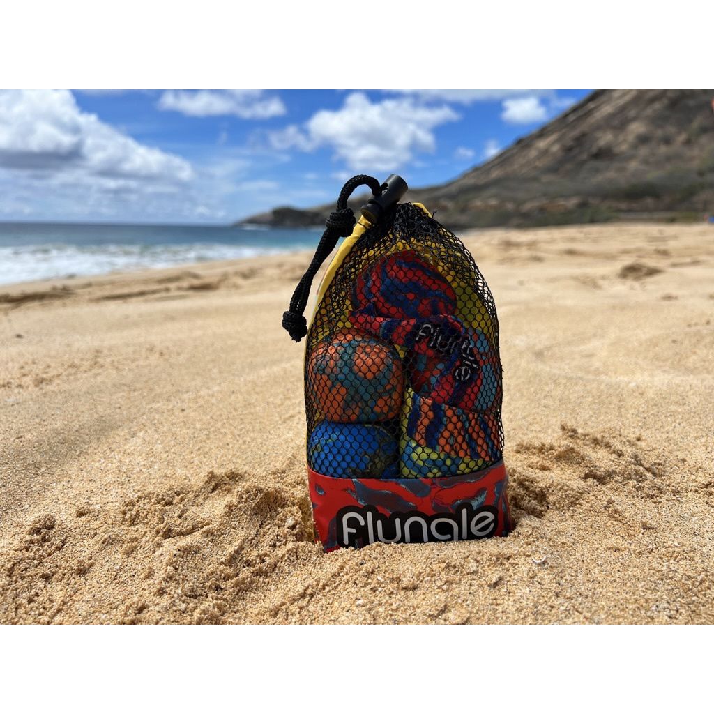 Gra zręcznościowa Waboba Flungle w siateczkowym opakowaniu na piaszczystej plaży z górskim tłem