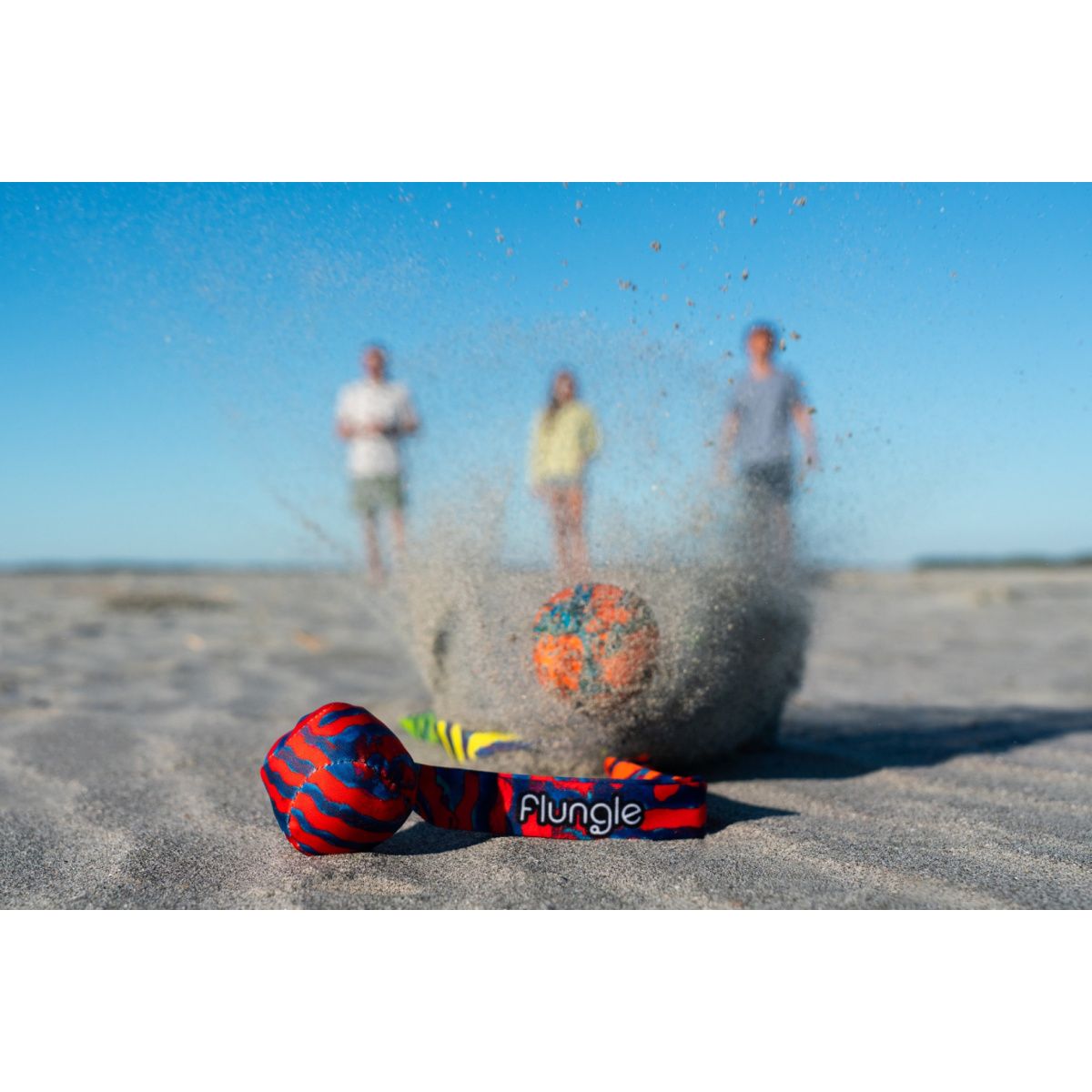 Gra zręcznościowa Waboba Flungle na piasku podczas zabawy na plaży trzech osób