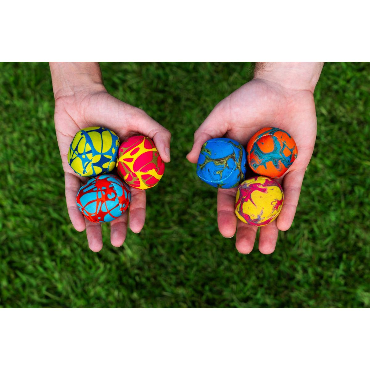 Gra zręcznościowa Waboba Flungle zestaw kolorowych piłek trzymanych w dłoniach na tle trawy