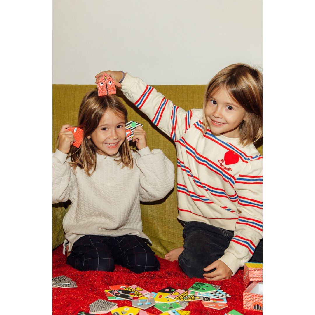 Dwie dziewczynki bawiące się grą memory domki dla dzieci na czerwonym dywanie z kartami z domkami