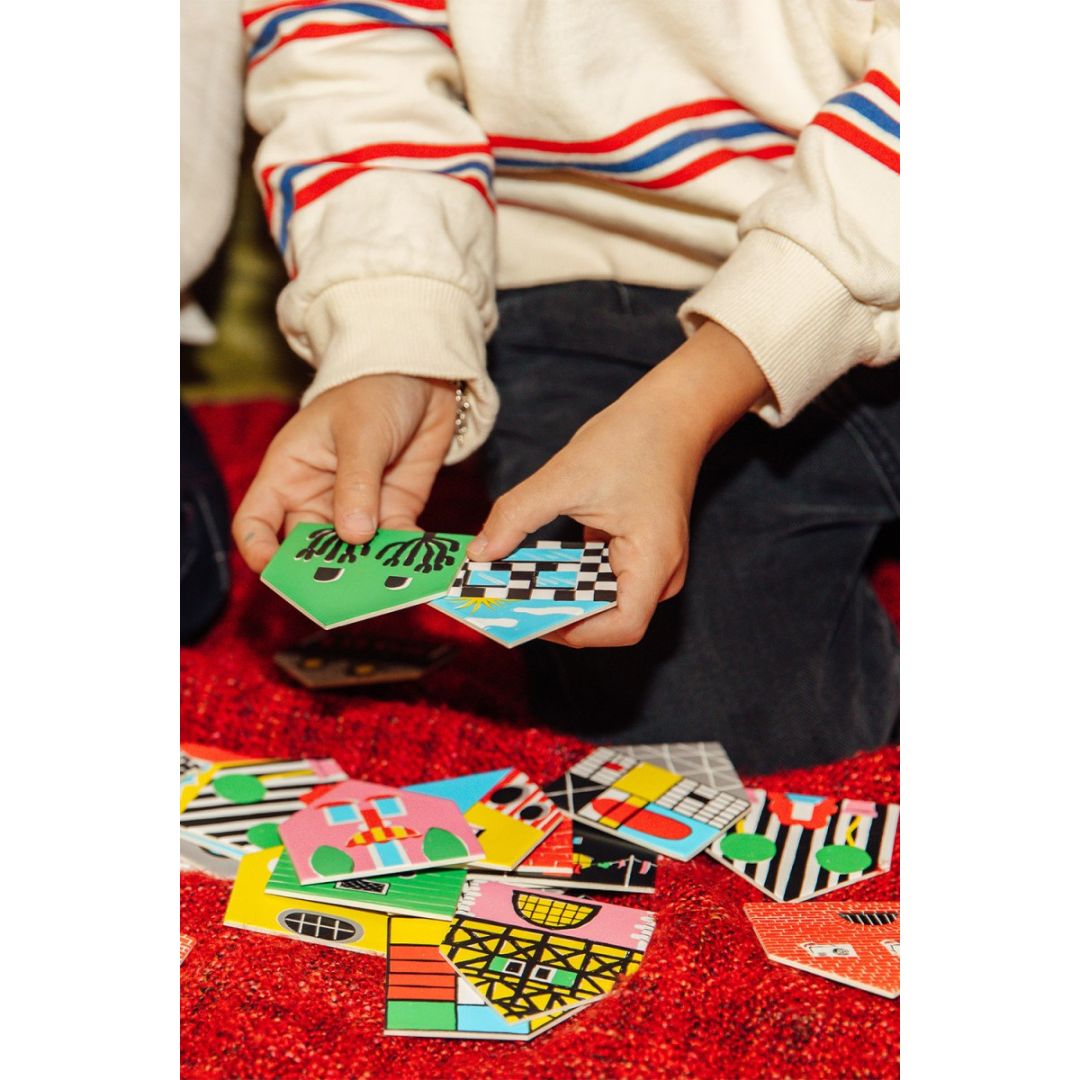 Dziecko bawiące się kolorową grą memory domki dla dzieci na czerwonym dywanie