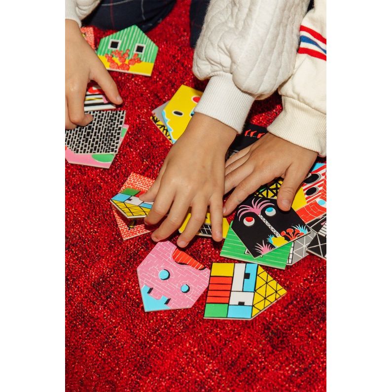 Dzieci bawiące się kolorową gra memory domki dla dzieci na czerwonym dywanie