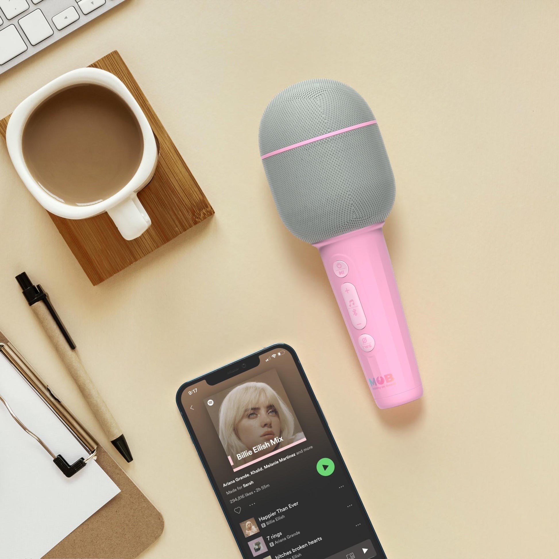 Różowy mikrofon bezprzewodowy z efektami wokalnymi WABOBA AB obok telefonu i filiżanki kawy