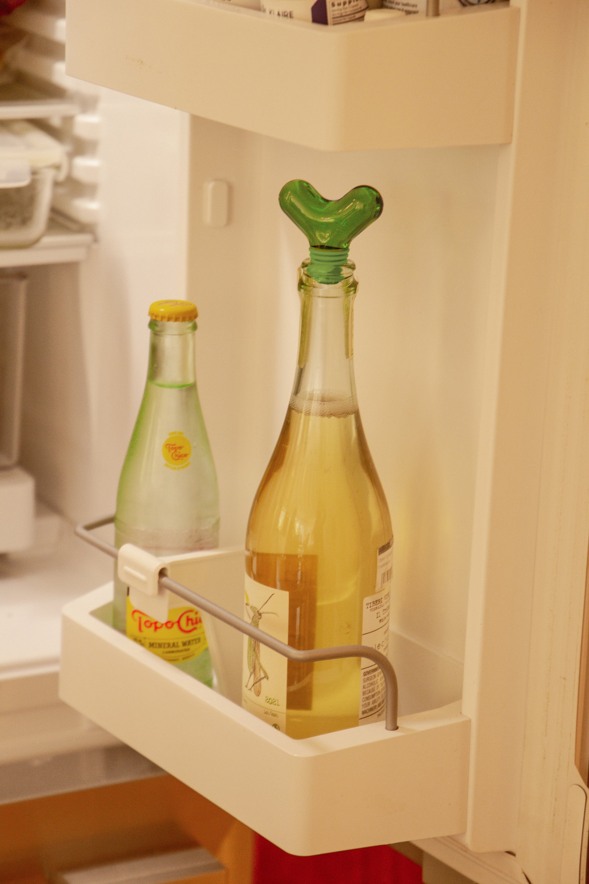 Korek do butelek zielony design na butelce w lodówce obok innej butelki z napojem