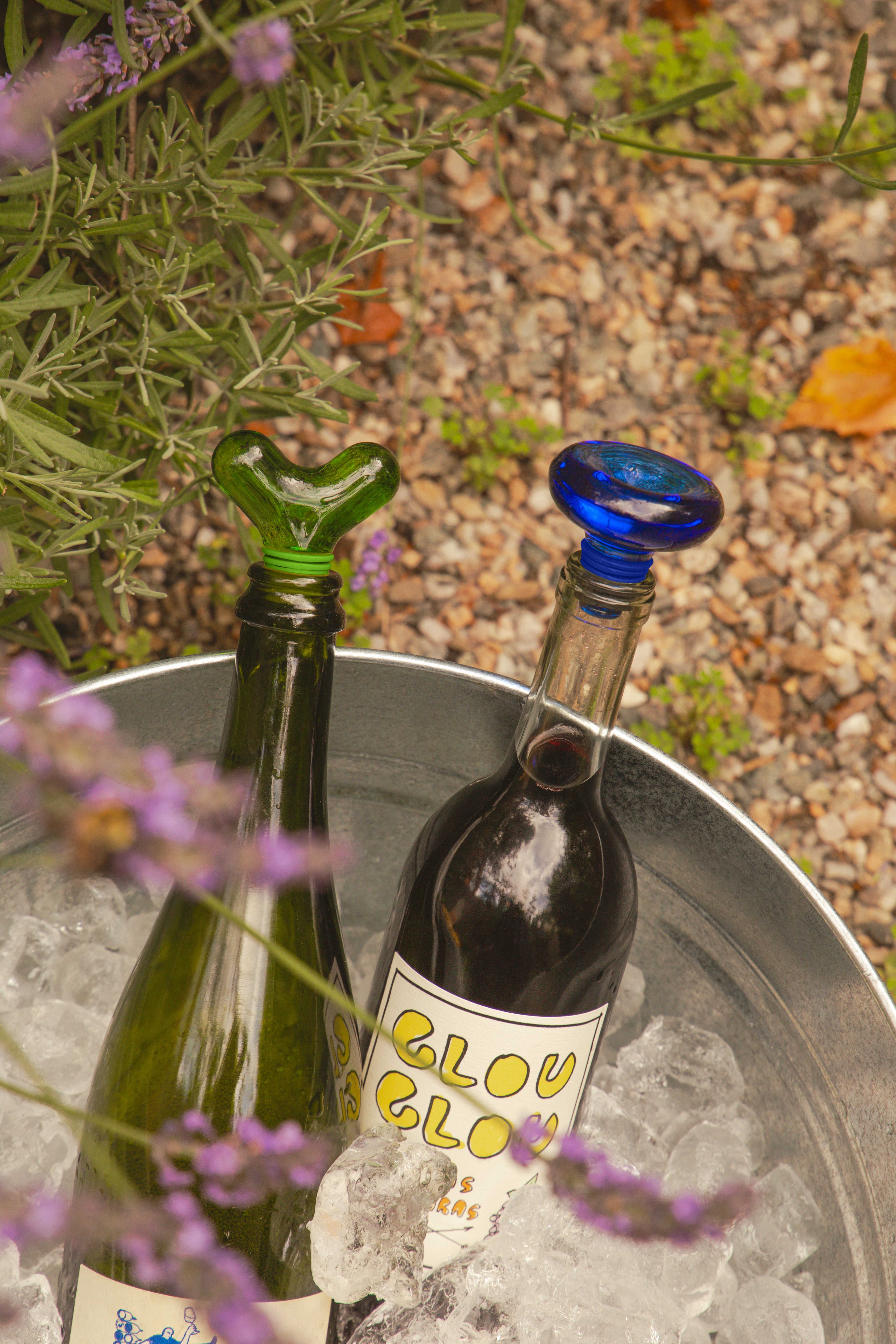 Niebieski korek do butelek Areaware na butelce w wiadrze z lodem na zewnątrz