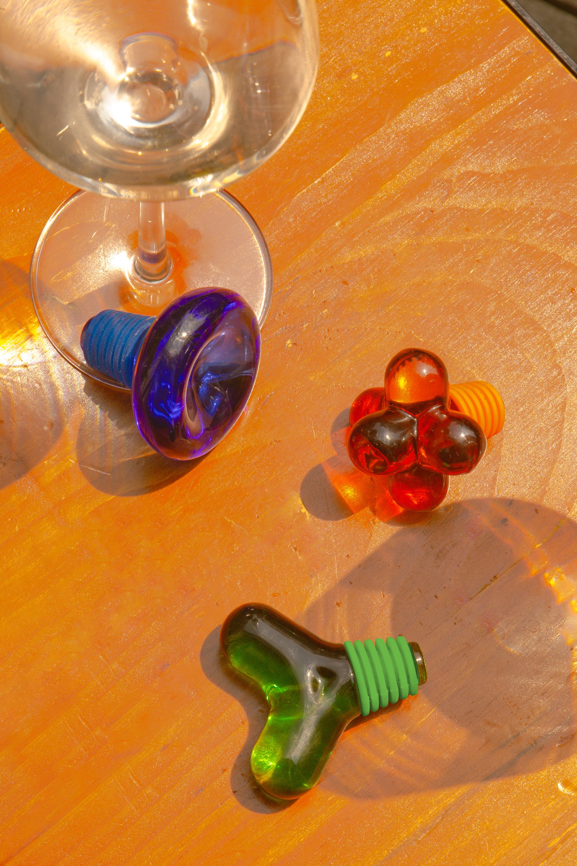 Korek do butelek designerski Areaware w kolorach zielonym, czerwonym i niebieskim na drewnianym stole