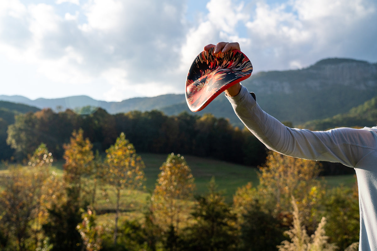 Osoba trzymająca frisbee Waboba Wingman Pro na tle górskiego krajobrazu podczas słonecznego dnia