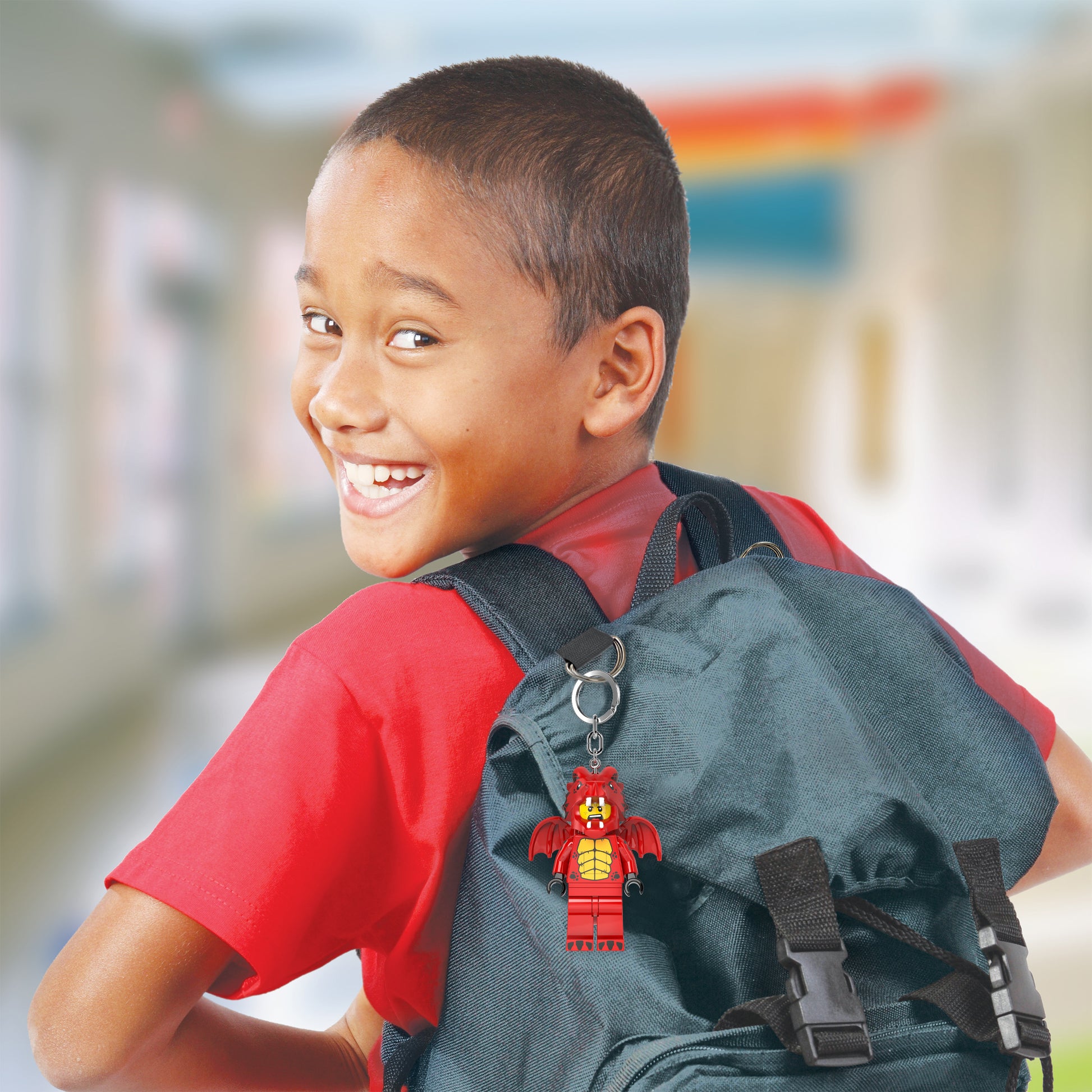 Chłopiec z szarym plecakiem ozdobionym brelok z latarką LEGO smok firmy MOB