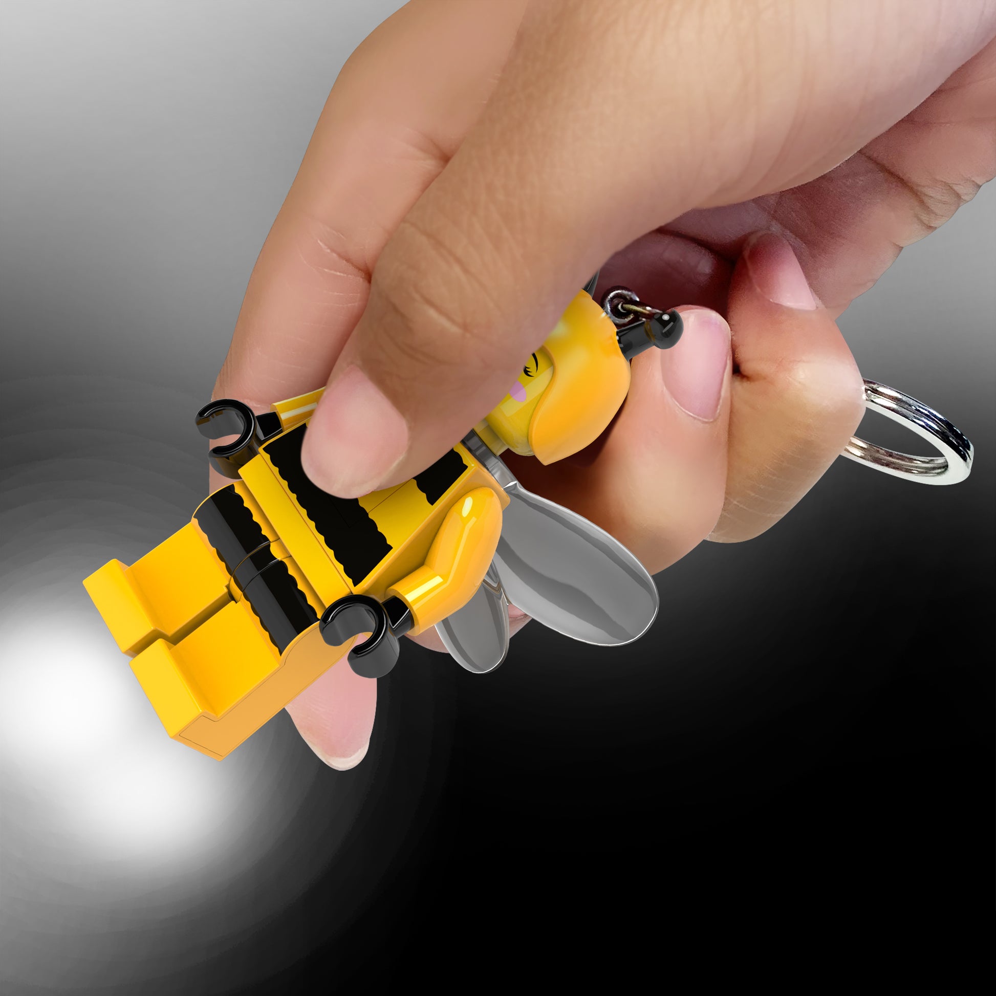 brelok z latarką LEGO Pszczółka w kształcie mini figurki trzymany w dłoni z włączoną latarką