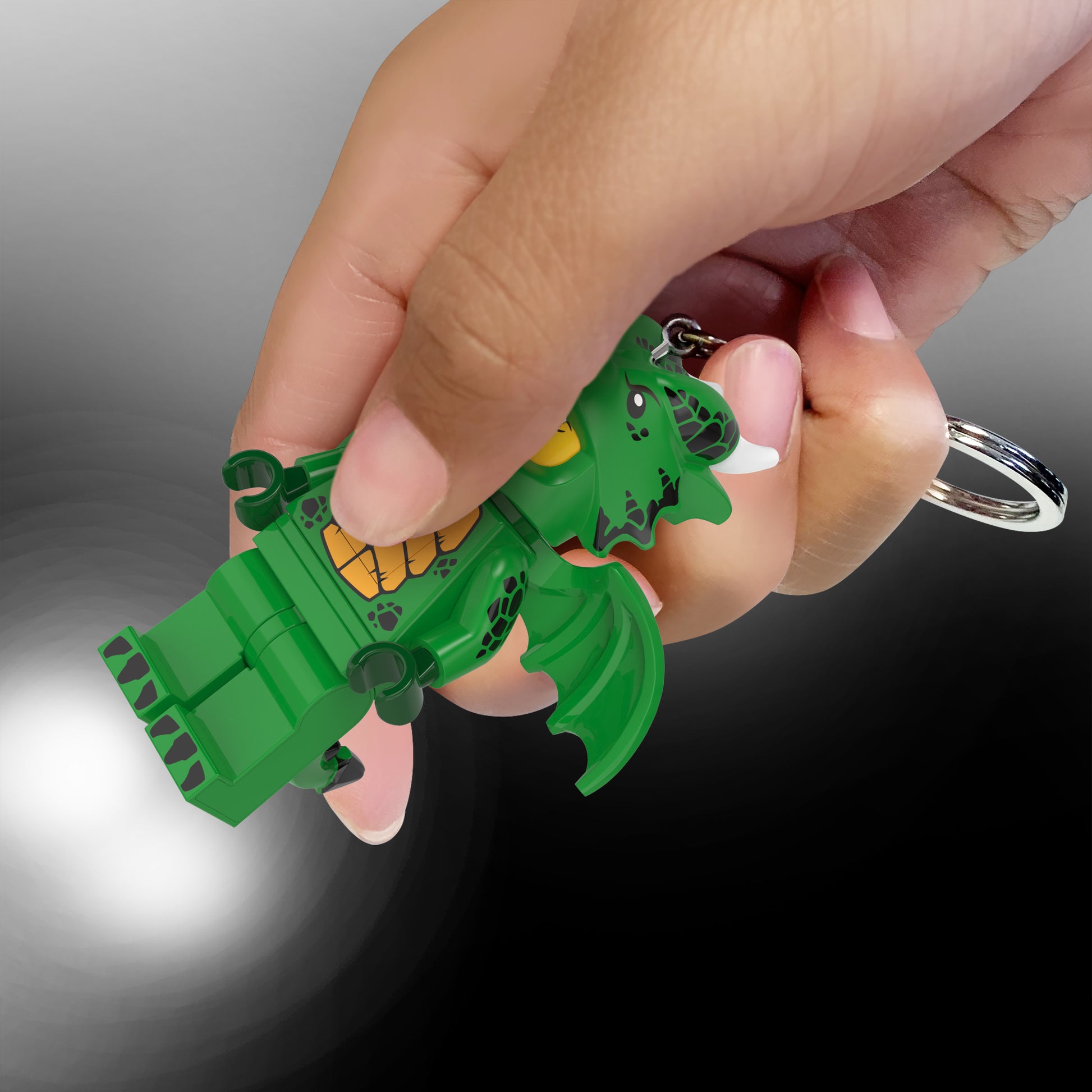 brelok z latarką LEGO Zielony Smok w kształcie smoka trzymany w dłoni z włączoną latarką