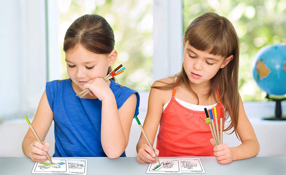 Dwie dziewczynki kolorujące obrazki używając kredek LEGO 12 sztuk w jasnym pokoju z globusem