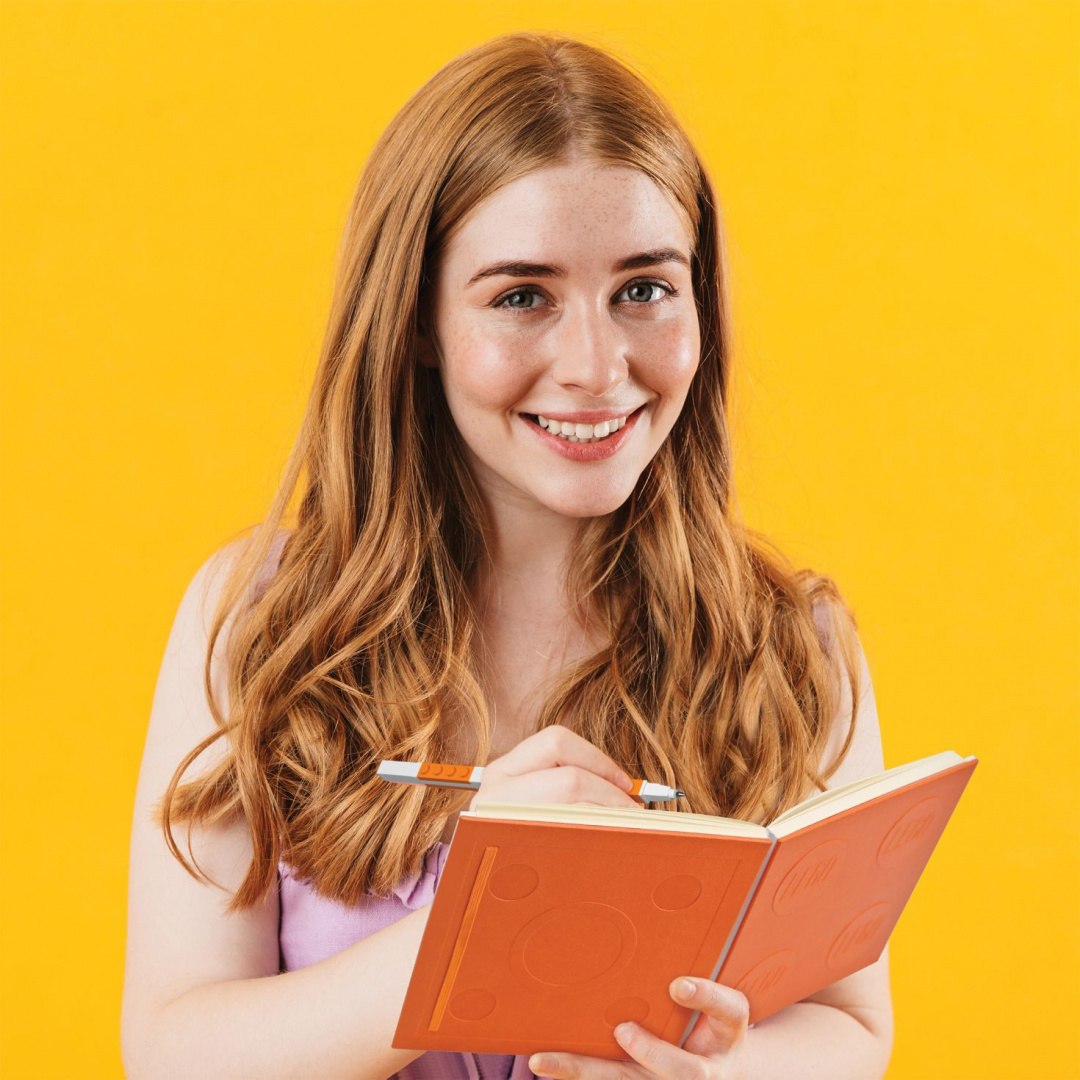 Kobieta pisząca w pomarańczowym notatniku LEGO fioletowy na żółtym tle