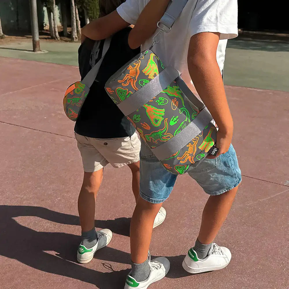 Torba weekender dla dzieci dinozaury w szaro-zielonej kolorystyce noszona przez chłopców na placu zabaw