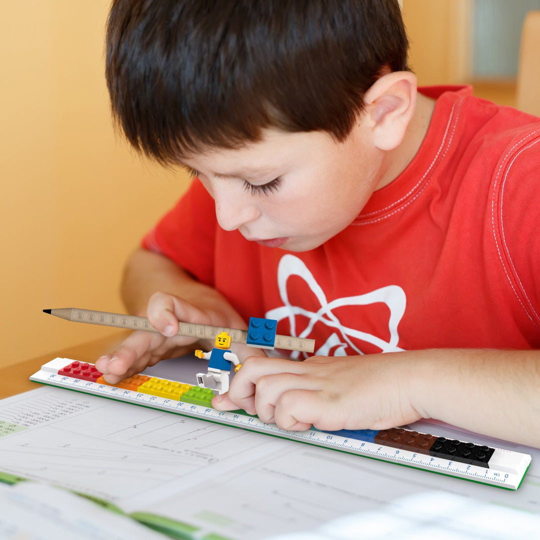 Chłopiec bawi się linijką LEGO do zbudowania na biurku podczas nauki