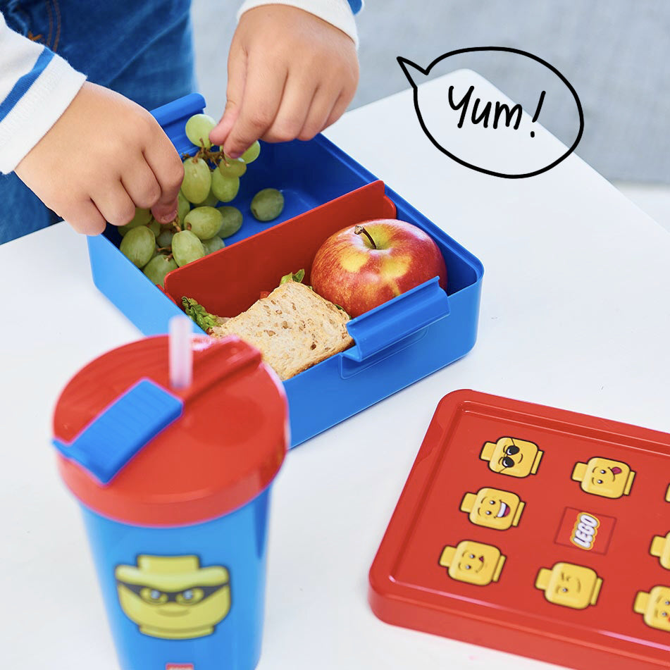 Lunchbox LEGO dla dzieci w niebieskim kolorze z przegrodą, jabłkiem, kanapką i winogronami