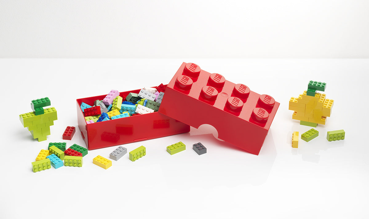 Lunchbox klocek LEGO czerwony w kształcie dużego klocka z rozsypanymi małymi klockami LEGO