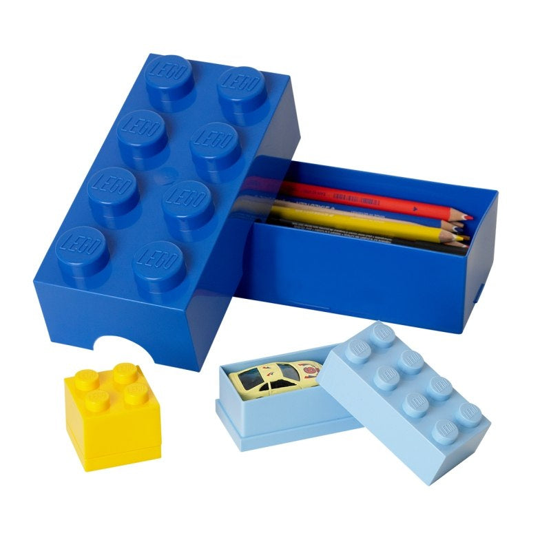 Niebieski lunchbox LEGO niebieski w kształcie klocka LEGO z otwartą pokrywą i kolorowymi kredkami w środku