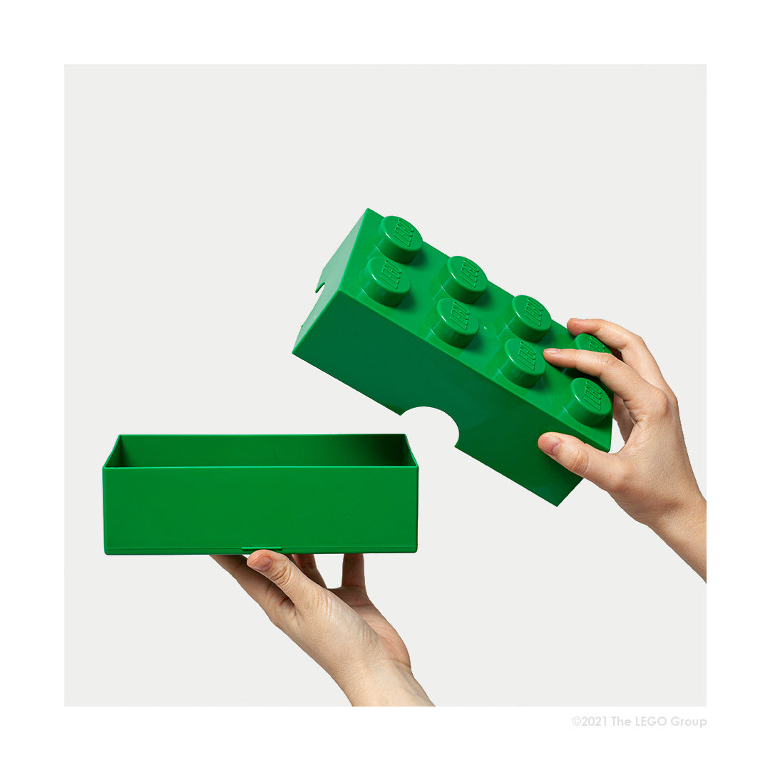 Lunchbox LEGO zielony w kształcie dużej klocka trzymany w dłoniach na białym tle